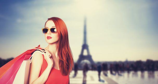 Paris arka plan üzerinde alışveriş torbaları ile Kızıl saçlı kadın. - Fotoğraf, Görsel
