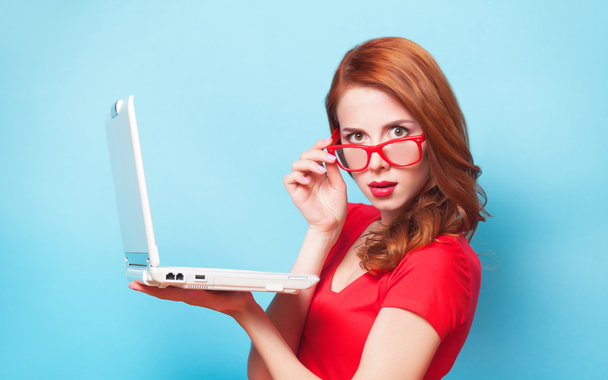Redhead girl with laptop on blue background. - Foto, Imagem