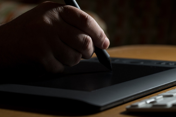 ruka držící grafické pero nad stůl - Fotografie, Obrázek
