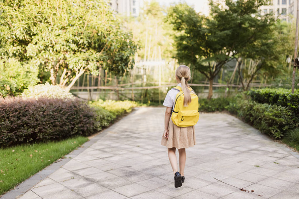 Yaz tatilinden sonra okula geri dönen kız öğrenci. Sabahın köründe üniformalı bir öğrenci dışarıda gülümsüyor..  - Fotoğraf, Görsel