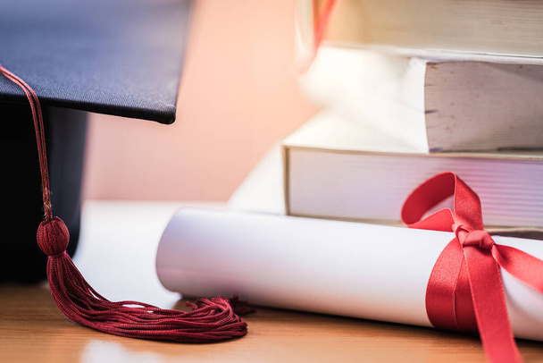 Zastřižená fotka minometu a diplomu z vysokoškolského postgraduálního klobouku na stole - Fotografie, Obrázek