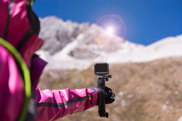 χέρι ταξιδιώτη γυναίκα κρατώντας κάμερα δράσης στο βουνό χιόνι, Πλοήγηση για ταξίδια, Κοντινό πλάνο - Φωτογραφία, εικόνα