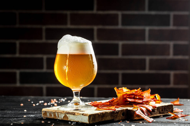 Frosty glass of craft beer with thick foam. dried fish on wooden background. Beer brewery concept. Snack for beer dried smelts. Beer background - 写真・画像