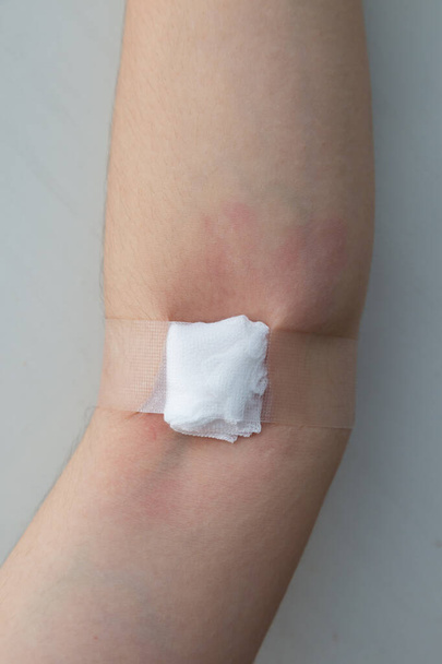 woman hand with cotton alcohol closed on arm after blood donation on white backgrpund - Photo, Image