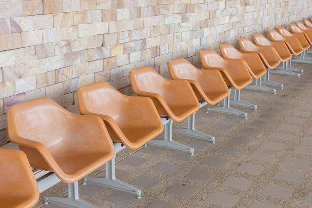 Reihe leerer Sitze mit Steinmauer als Hintergrund - Foto, Bild