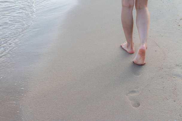 Voyage à la plage seul - femme marchant seule sur la plage de sable laissant des empreintes de pas dans le sable Détail rapproché des pieds féminins et fond de sable doré - Photo, image