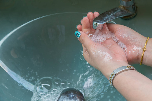 Las mujeres se lavaban las manos con jabón líquido bajo el agua corriente y llevaban brazalete de oro y anillo de oro - Foto, Imagen