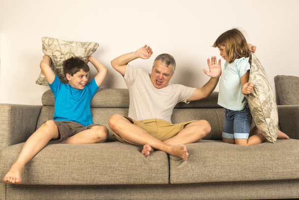 Papà e bambini litigano insieme con i cuscini
 - Foto, immagini