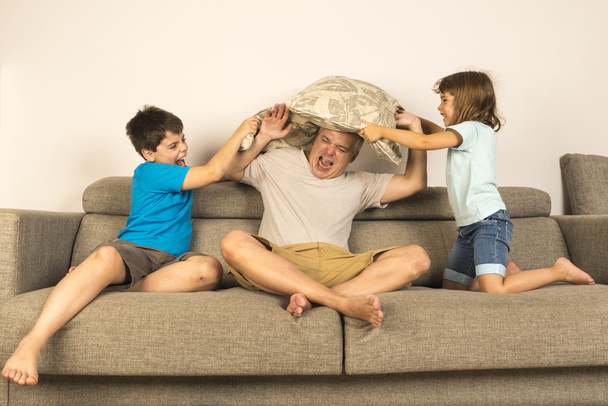 Papá y los niños peleando juntos con almohadas
 - Foto, imagen