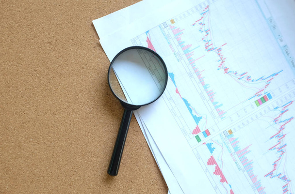 magnifying glass and graph document report on  brown desk at office  .Finance  business and research concept  - Photo, Image