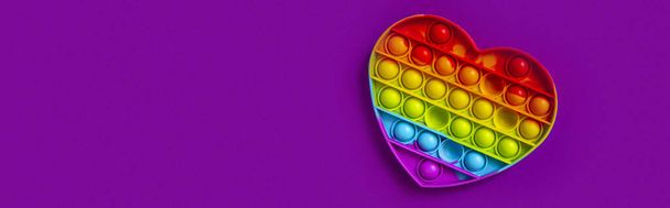 Colorful sensory toy fidget push pop it heart on purple background - Photo, Image