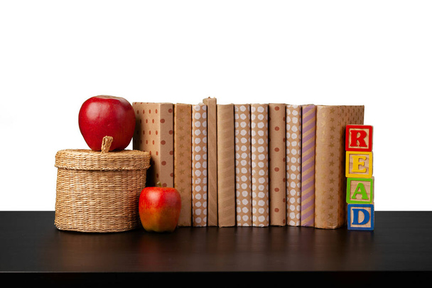 Stack of books and apple on tabletop against white background - Photo, image