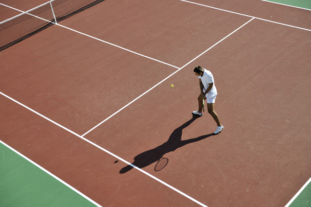Young man play tennis outdoor on orange tennis field at early morning - Φωτογραφία, εικόνα