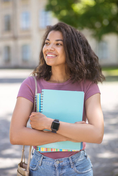 A picture of a girl in a pink tshirt holding textbooks in her hands - Foto, imagen