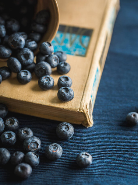 Atmospheric shot of ripe blueberries on the old book. Selective focus. Shallow depth of field. - Фото, зображення
