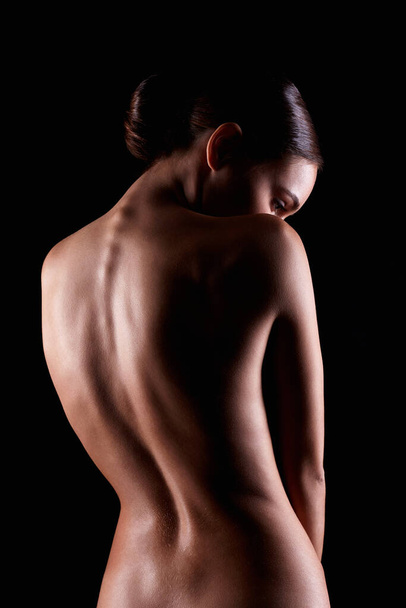 Γυναικεία γυμνή σιλουέτα. Γυμνή γυναίκα. Αισθησιακό κορίτσι στο σκοτάδι. Όμορφη πλάτη - Φωτογραφία, εικόνα