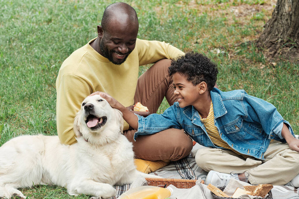 Family sitting with dog outdoors - Photo, image