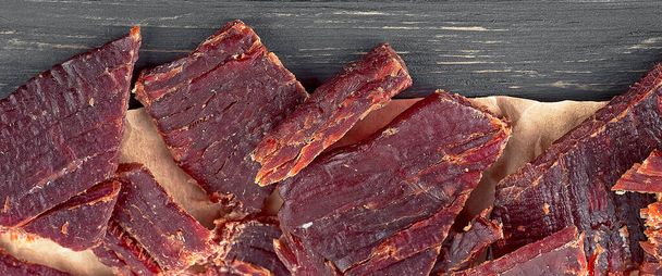 Close up view of beef jerky pieces on a wooden table, top view. - Foto, afbeelding