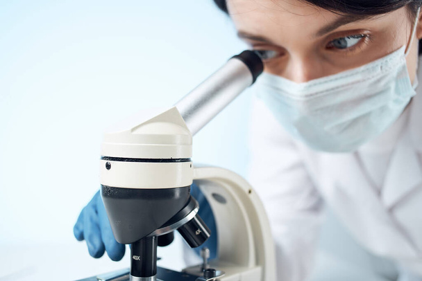 médecin avec masque médical regardant à travers une expérience de laboratoire de microscope - Photo, image