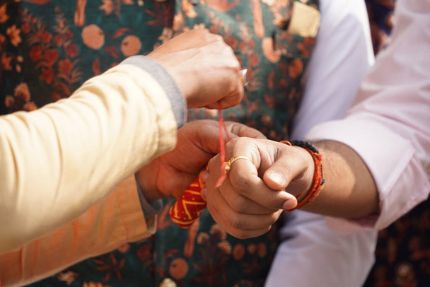 um homem a amarrar uma banda de amizade no pulso de outro homem. rakhi masculino ou rakshabandhan conceito imagem da tradição indiana - Foto, Imagem