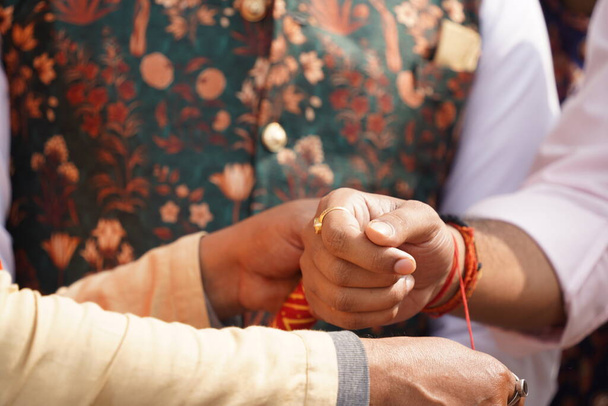 Ένας άντρας που δένει τη ζώνη φιλίας στον καρπό ενός άλλου άντρα. Αρσενικό rakhi ή rakshabandhan έννοια εικόνα της ινδικής παράδοσης - Φωτογραφία, εικόνα