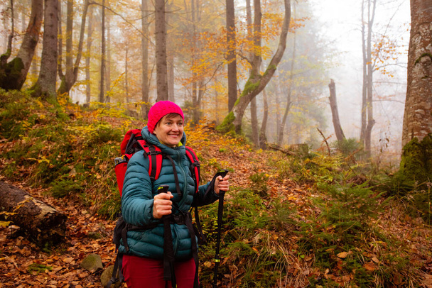 Happy woman hiker is walking in the beautiful autumn forest - Foto, Imagem