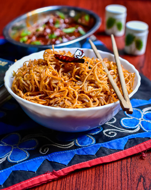 A selective focus image of a bowl of spicy Schezwan Noodles prepared with Indian spices. - Photo, image