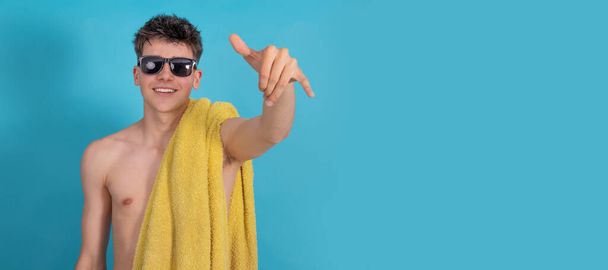 jovem com óculos de sol e toalha sorrindo isolado com gesto surfista - Foto, Imagem