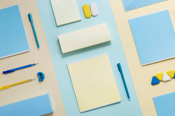 Stationary school supplies in yellow and blue tone. Office accessories notepads, pencil box, pens, pencils, erasers on paper background. Flat lay minimal. - Фото, изображение