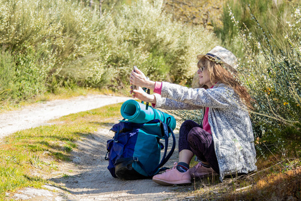 женщина с рюкзаком практикуется походы с мобильного телефона - Фото, изображение