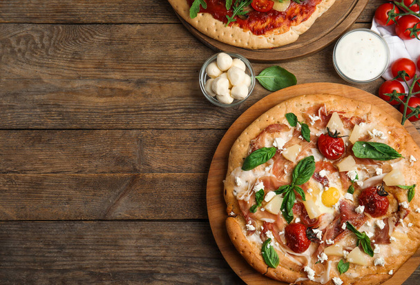 Delicious pita pizzas with prosciutto, pineapple, grilled tomatoes and egg on wooden table, flat lay. Space for text - Zdjęcie, obraz