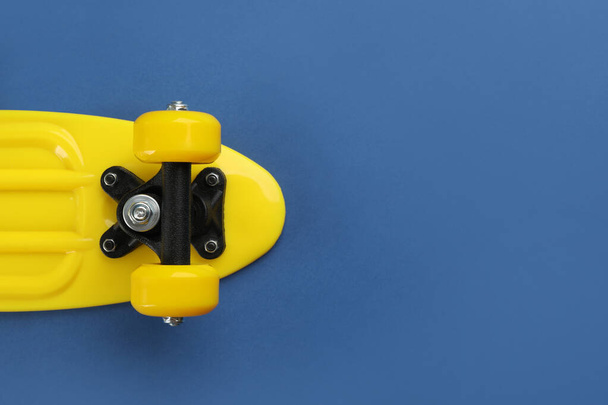 Yellow skateboard on blue background, top view. Space for text - Foto, Imagem