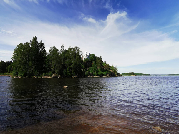 View from the shore of the Ludwigsburg Chapel on Ludwigstein Island in the Monrepos Rock Nature Park of Vyborg against a beautiful blue sky with clouds. - Photo, Image