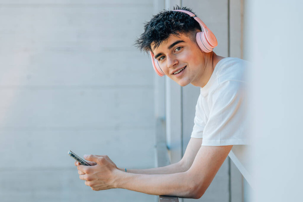 adolescent garçon avec téléphone portable et écouteurs sur le balcon - Photo, image
