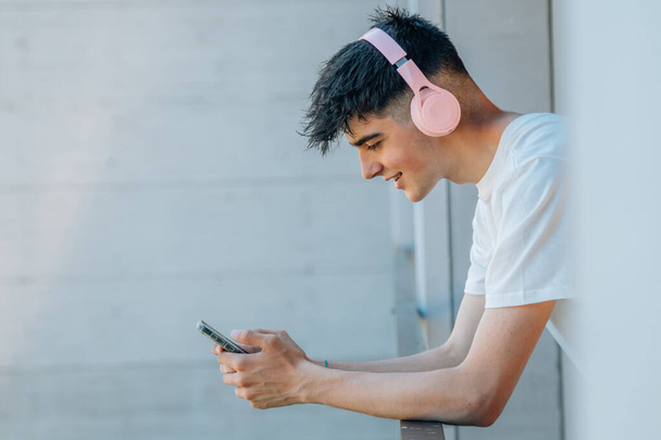 nastolatek z telefonem komórkowym i słuchawkami na balkonie - Zdjęcie, obraz