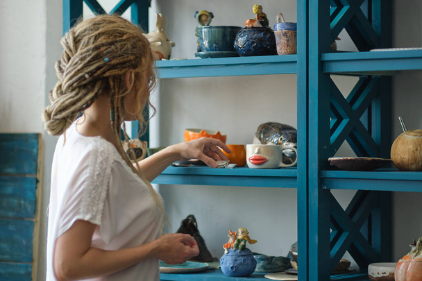 Gastgeberin der Keramikwerkstatt legt ihr keramisches Geschirr in den Regalen aus. Feng Shui Konzept. Büro für Kleinunternehmen - Foto, Bild