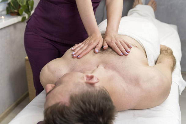 Herstellende massage van de mannelijke borst. Wellnessbehandeling in de spa. Ontspannende spabehandeling. - Foto, afbeelding