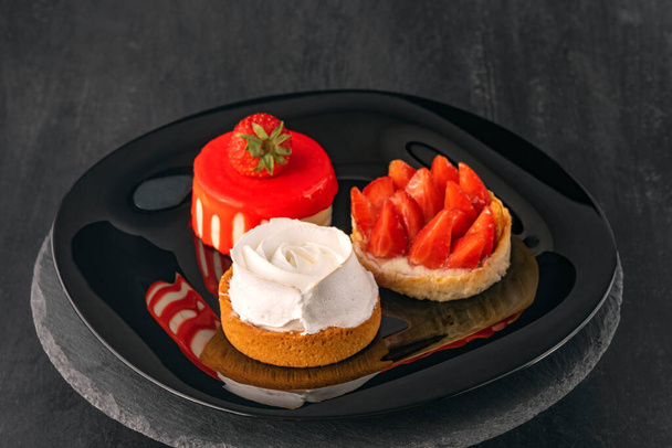 Trois gâteaux sur plaque noire. Desserts aux fruits avec fraises fraîches. Des confiseries. Desserts délicats. - Photo, image