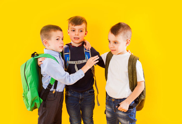 Cute schoolboys in uniform with backpacks on yellow background - Foto, immagini