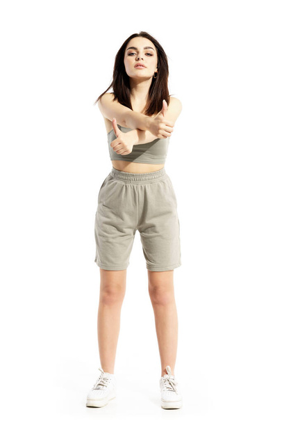 Überhebliche Haltung junge schöne Sommer Frau zeigt Daumen nach oben mit verschränkten Armen. Ganzkörperporträt isoliert auf weißem Hintergrund - Foto, Bild