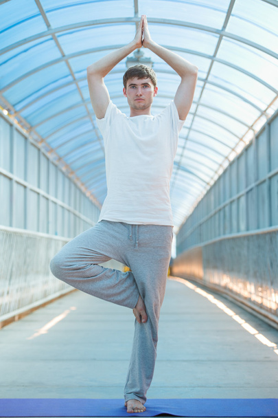 Man practices yoga on the bridge - Valokuva, kuva
