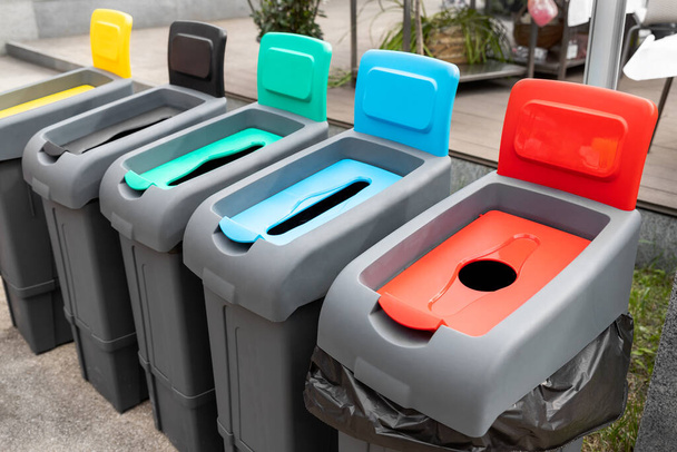 Řada různých různobarevných plastových kontejnerů na třídění a recyklaci odpadu ve venkovních ulicích města. Ochrana životního prostředí a ochrana přírody před nebezpečím zamoření - Fotografie, Obrázek
