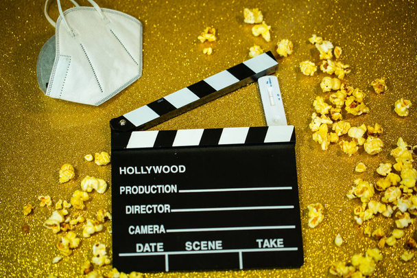 Portello cinema con popcorn, test Covid e maschera, su sfondo dorato - Foto, immagini