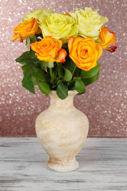 Beautiful bouquet of roses in vase on table on brown background - Fotó, kép