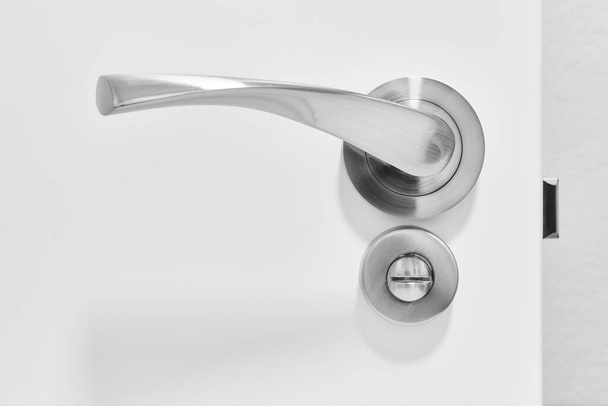 Metallic doorknob and bolt on a white wooden door. Detail - Photo, Image