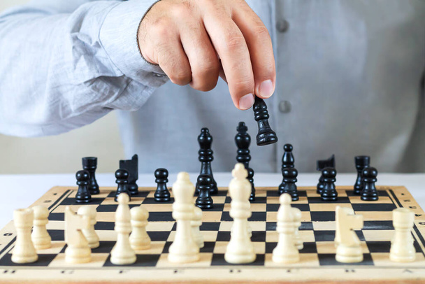 Man playing chess game, hand moving chess piece on chessboard. Success financial business strategy concept - 写真・画像