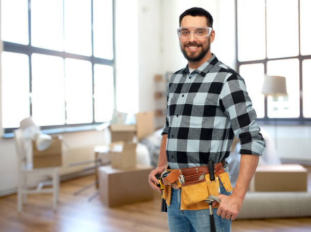 happy male builder with tool belt at home - Fotoğraf, Görsel