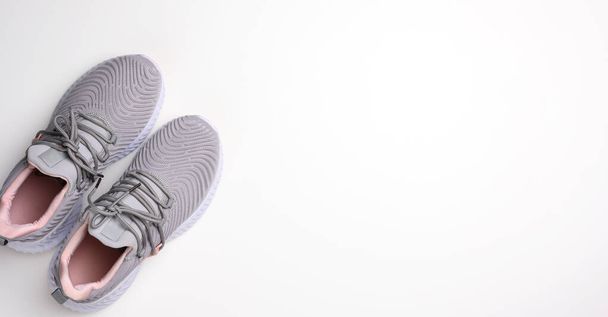 egy pár szürke textil tornacipő fehér háttérrel, felülnézetből. Sportcipő, kocogás - Fotó, kép