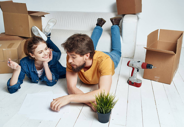 un uomo e una donna si trovano sul pavimento in movimento scatole nuove abitazioni - Foto, immagini