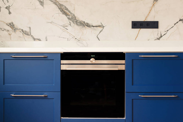 Luxury blue kitchen with marble tiled backsplash. Modern oven in stylish new kitchen. Modern kitchen clean interior design. - Photo, Image